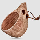 An Original 8oz. Kuksa from Überleben. The natural hardwood cup flaunts a honeycomb pattern and a looped leather strap attached to the handle.